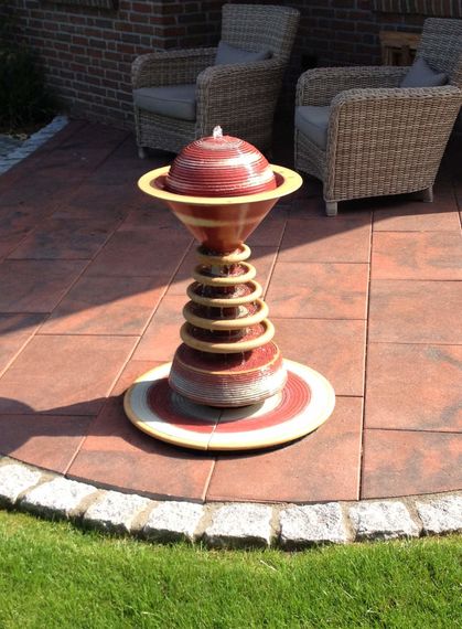 Moderner Gartenbrunnen aus winterfester Keramik mit gerillter Säule und kaskadenförmigen Tellern rot-weiß, dezente Akustik