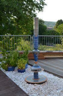 Terrassenbrunnen Design aus winterfester Keramik mit gerillter Säule und Lichtreflexen über zwei farbige Kegel, dezente Akustik