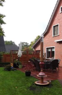 Moderner Gartenbrunnen aus winterfester Keramik mit gerillter Säule und Lichtreflexen über zwei farbige Kegel, dezente Akustik