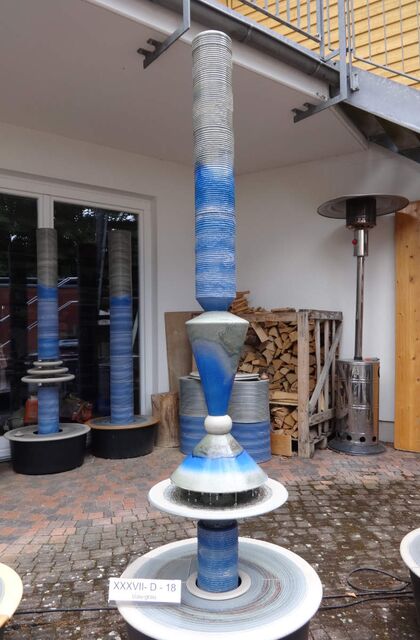 Designerbrunnen vom Künstler mit gerillter Säule und Lichtreflexen über zwei farbige Kegel, dezente Akustik  blau-grau