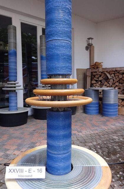 Designerbrunnen vom Künstler mit gerillter Säule und kaskadenförmiges Abtropfen über Teller, dezente Akustik