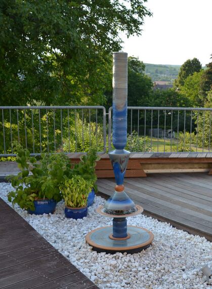 Terrassenbrunnen Design aus winterfester Keramik mit gerillter Säule und Lichtreflexen über zwei farbige Kegel, dezente Akustik