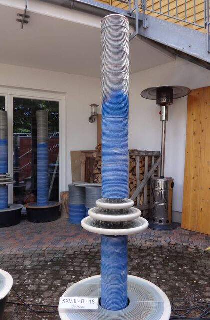 Designerbrunnen vom Künstler mit gerillter Säule und kaskadenförmiges Abtropfen über Teller, dezente Akustik